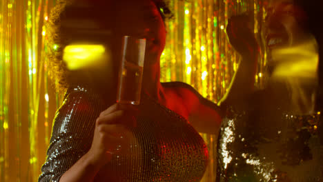Close-Up-Of-Two-Women-Dancing-In-Nightclub-Bar-Or-Disco-Drinking-Alcohol-With-Sparkling-Lights-21